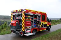 rotes Feuerwehrfahrzeug mit ge&ouml;ffneten Ladeklappen